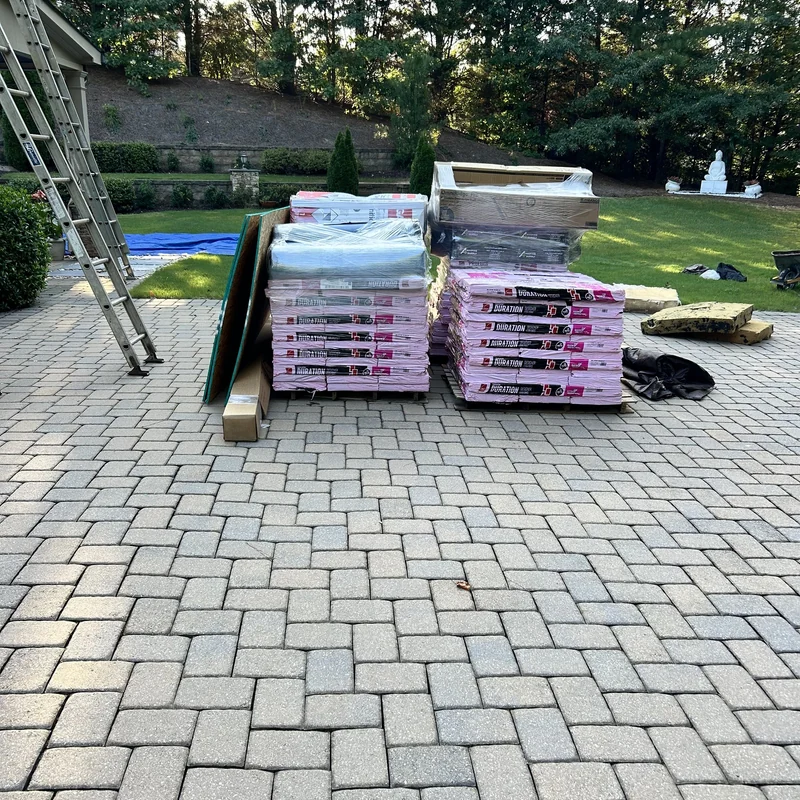 Owens Corning Duration shingles, decking and wrapped roofing accessories on a paved patio.