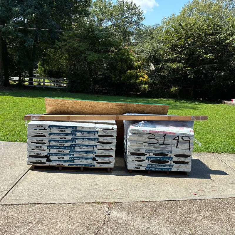 IKO Cambridge shingle pallets with roof decking and trim delivered to a residential driveway.