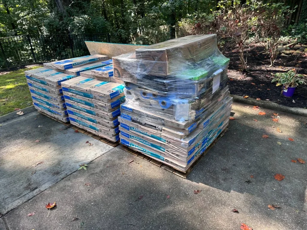 CertainTeed Landmark shingle bundles and wrapped roofing supplies on pallets beside a driveway.