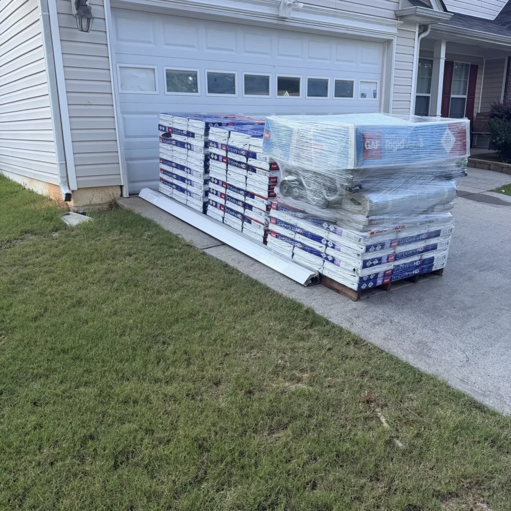 GAF Timberline HDZ bundles and a Cobra SnowCountry box on pallets in front of a garage.